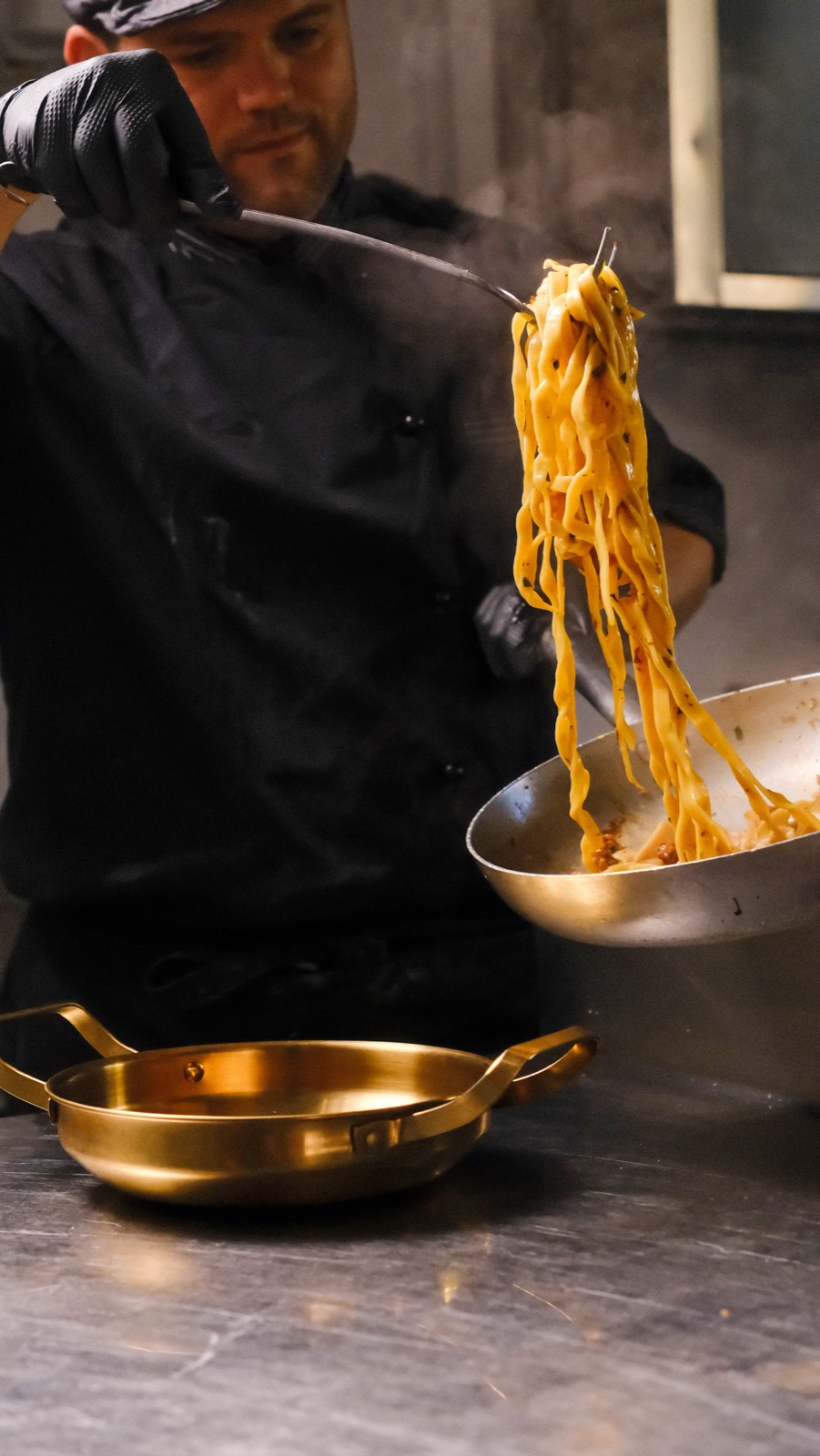 Lo chef solleva le tagliatelle dalla padella