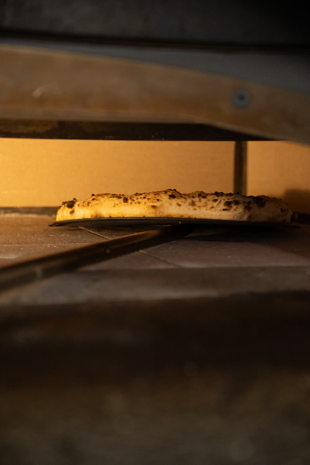 Una pizza sulla pala davanti alla bocca del forno