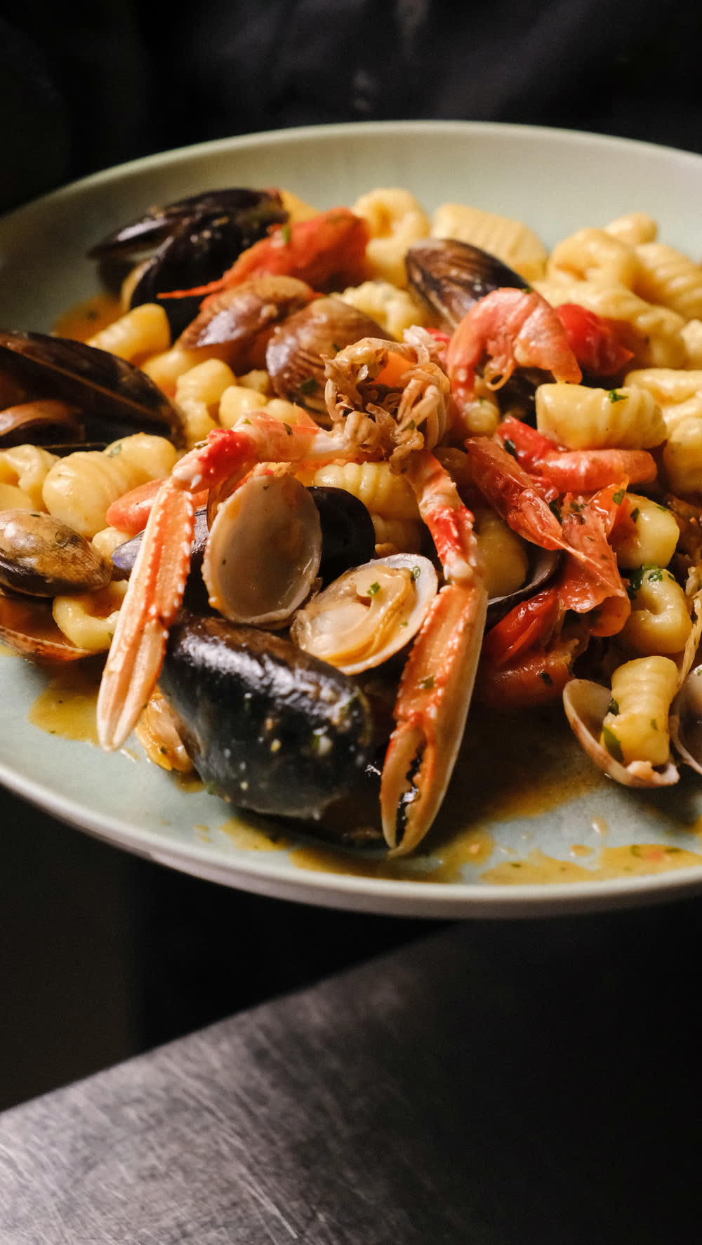Pasta con frutti di mare, cozze, vongole e crostacei, servita in un piatto verde