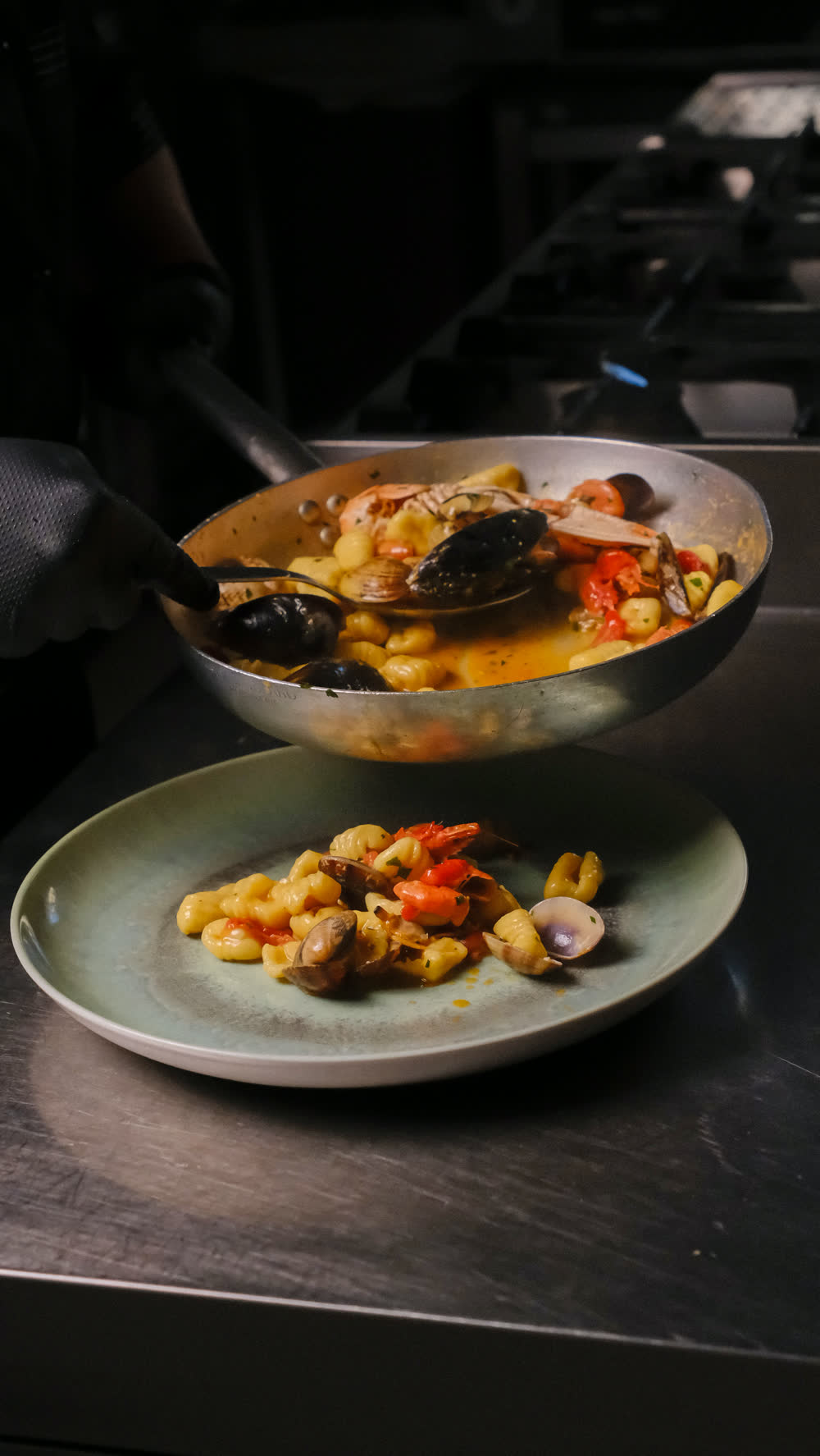 Due piatti di pasta con frutti di mare appena impiattati in cucina