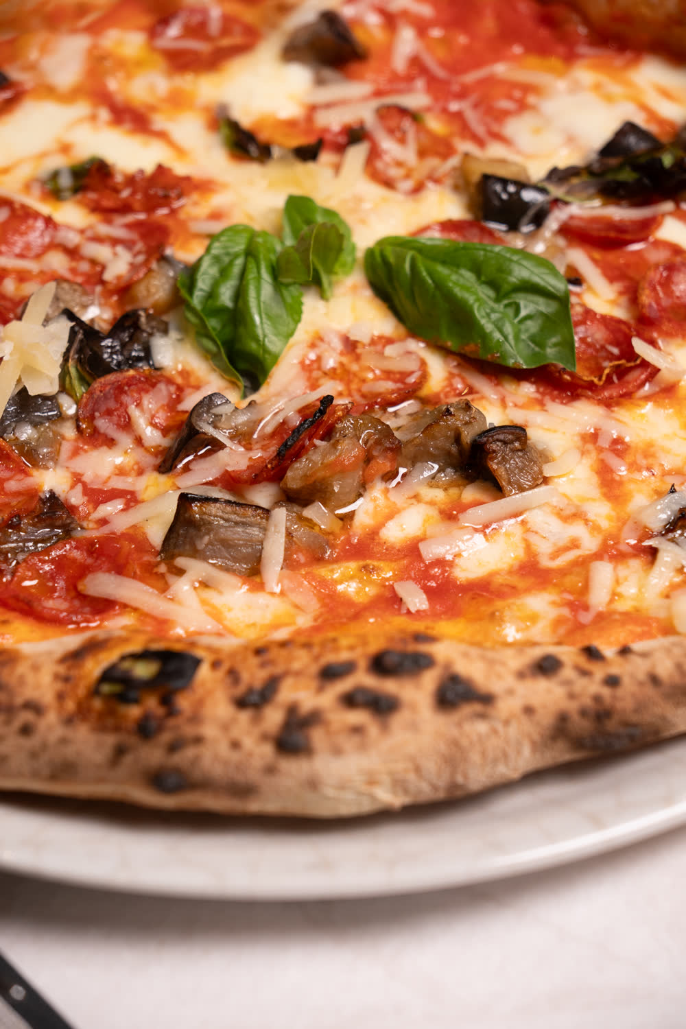 Primo piano di una pizza con pomodoro, mozzarella e basilico